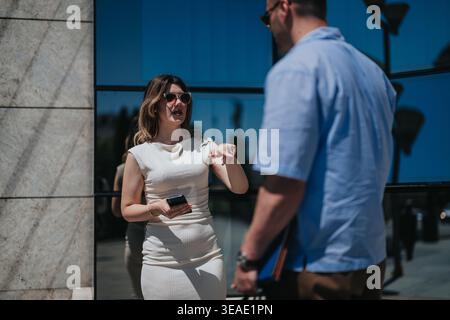 Business meeting between two professionals conversing outside a modern glass office building Stock Photo