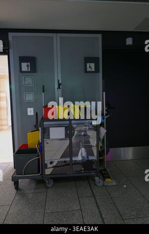 Cleaning cart in airport near restroom doors, hygiene service and maintenance concept in travel terminal. Stock Photo
