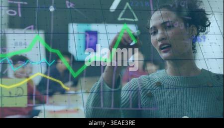 Writing woman wearing knit sweater drawing on glass board with bright charts in office, copy space Stock Photo