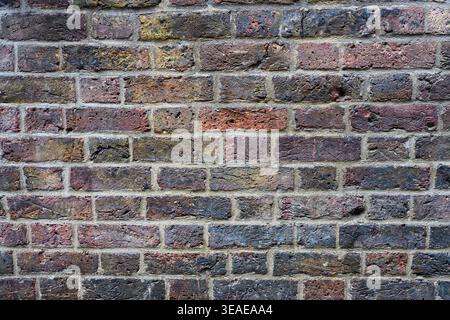 Weathered multi colored rough texture brick wall background with dirt and grim of ageing Stock Photo