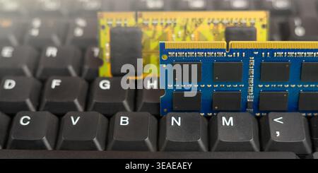 Two memory modules are sitting on a black keyboard in a home office while someone works on a technology project. Stock Photo