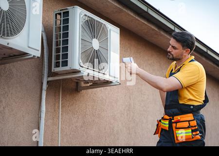 Technician using infrared thermal gun to check air conditioning unit Stock Photo