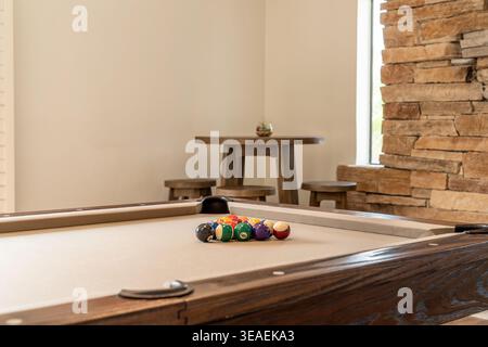 Close-up pool table with racked balls and wooden bar stools and table in the background Stock Photo