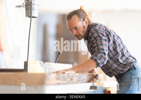 Woodworker carefully operating woodworking machine in workshop Stock Photo