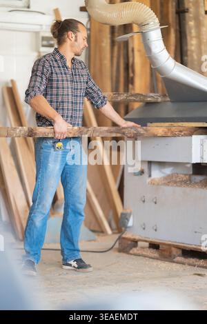 Carpenter working with wood plank using planer machine Stock Photo