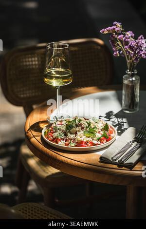 Mediterranean salad with wine on sunny table Stock Photo