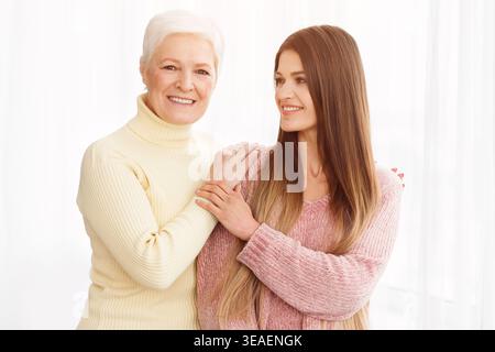 Older mother and daughter posing and looking at camera Stock Photo