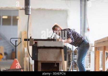 Carpenter man working on wood with machinery in workshop Stock Photo