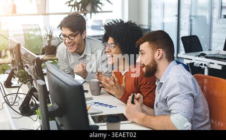Three young men enjoying good coding job on computer Stock Photo