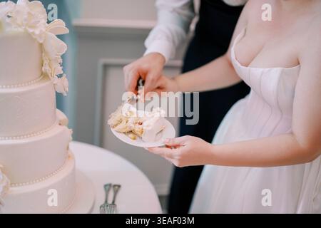 Intimate moment with cake and heartfelt emotion. Couple shares first slice with gentle guidance and joyful expression Stock Photo