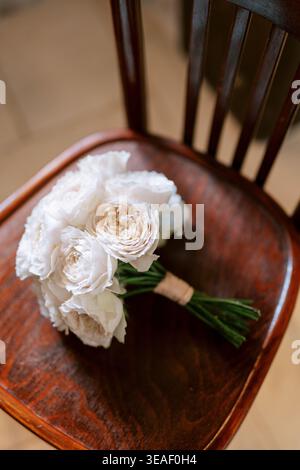 Elegant floral display. Romantic scene featuring white roses on vintage seat with warm natural illumination Stock Photo