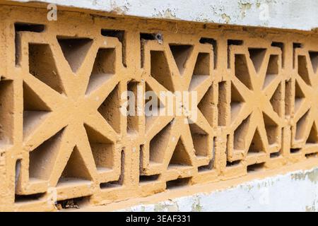 Close-Up Of Decorative Yellow Concrete Breeze Block Wall With Geometric Star Pattern And Weathered Texture Stock Photo