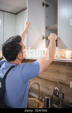 Handyman Installing or Repairing Kitchen Cabinet Door Hinge Stock Photo