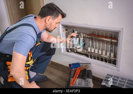 Technician taking pictures of heating pipes using smartphone for remote assistance Stock Photo