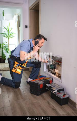 Plumber inspecting pipes and talking on the phone Stock Photo