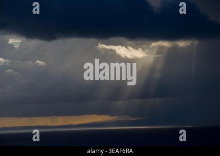 Sunbeams Breaking Through Dark Storm Clouds Over Ocean Stock Photo
