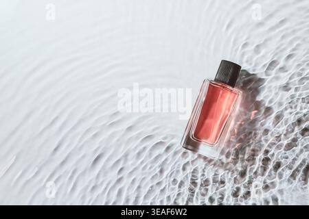 Perfume bottle laying on dynamic water surface creating elegant cool reflections Stock Photo