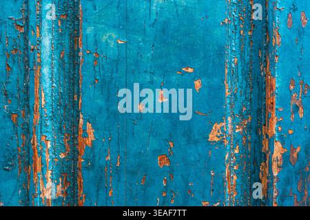 Close-up of weathered blue wooden door texture with peeling paint and rustic orange accents. Stock Photo