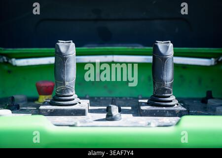 Dual joystick controls on green construction machine operator panel, industrial equipment cockpit detail for machinery handling, fleet maintenance and Stock Photo