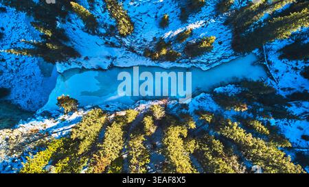 Aerial Frozen Waterfall and Snowy Pine Forest in Winter Top Down Stock Photo