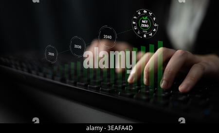 A close-up image of hands typing on a keyboard with a graph depicting net zero emissions goals, creating a powerful visual narrative about sustainabil Stock Photo
