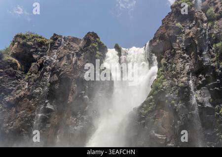 landscape with water falling on black rocks at tone of Mosqueteros jumps  at nature park, shot from below in bright summer light at Iguazu Waterfalls, Stock Photo
