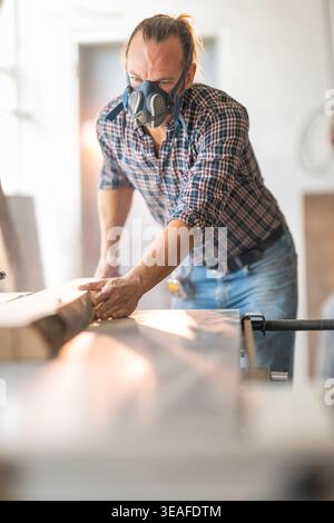 Woodworker flattening timber planks using a specialist woodworking machine Stock Photo