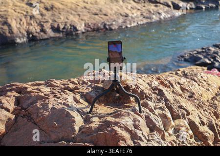 A Phone mounted on a flexible tripod to Record the Rocky River Nature Scene (Content Creation Concept) Stock Photo