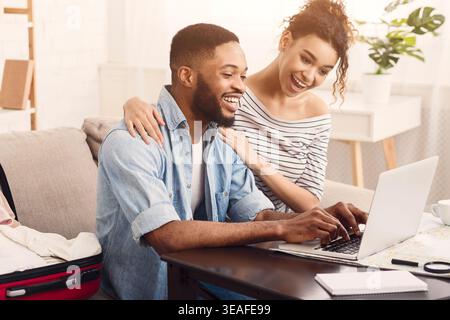 Couple Enjoying a Fun Moment Together While Working on a Laptop at Home Stock Photo