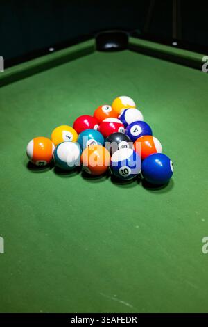 Close up of colorful pool balls in a triangle formation on a green felt table. Stock Photo