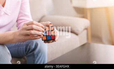 Person Solves Rubiks Cube While Sitting on a Couch in a Living Room During Afternoon Stock Photo
