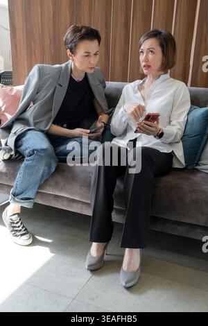 Colleagues discussing business topics and collaborating with smartphone in bright modern office. Colleagues, discussion, smartphone, business Stock Photo