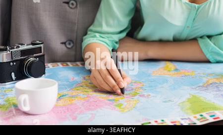 Group Planning a Trip Using a World Map With Camera and Cup of Coffee Nearby Stock Photo
