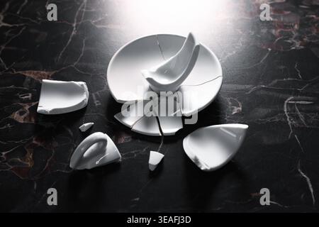 Pieces of broken saucer and cup on black table, closeup Stock Photo