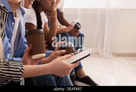Group of Young Adults Using Smartphones While Enjoying Coffee in a Cozy Indoor Setting Stock Photo