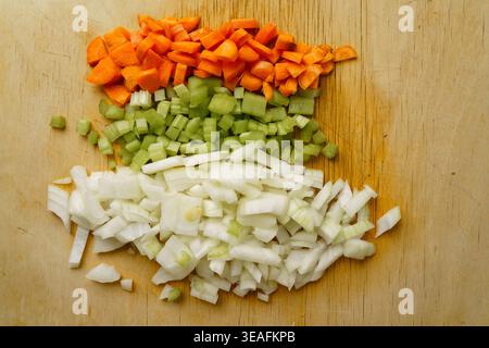 Top view of diced carrots, celery, and onions prepared for soffritto base on a wooden cutting board. Stock Photo