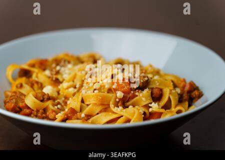 Tagliatelle pasta with ragu alla bolognese served in a light blue ceramic bowl. Stock Photo