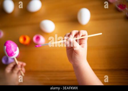 A child holding a brush, painting Easter eggs, acrylic paints, handicrafts, crafts with a child Stock Photo