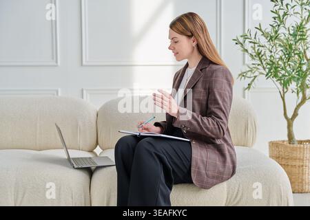 Young female online psychologist, mentor, teacher working remotely with laptop Stock Photo