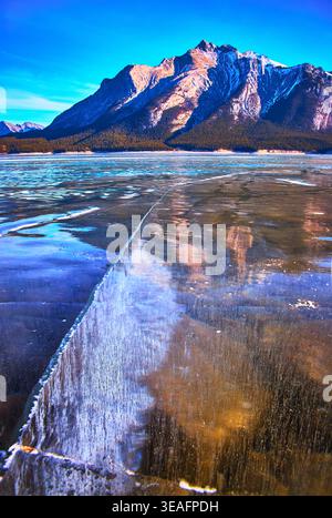 Frozen Lake Cracks and Icy Reflections with Majestic Mountain in Winter Stock Photo