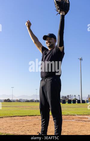 Vertical video: Male player raising arms after catching baseball on field, with motion speed HUD Stock Photo