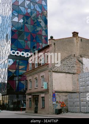 Modern Coop glass tower rising behind old stone and plaster buildings in Tallinn city center, Estonia, spring Stock Photo