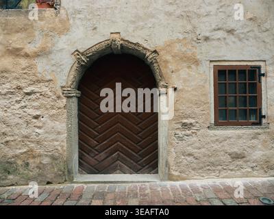 Medieval arched wooden door with herringbone pattern in limestone wall, Tallinn Old Town, Estonia Stock Photo