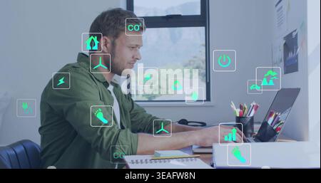 Working man in green shirt using laptop in home office with holographic energy icons, copy space Stock Photo