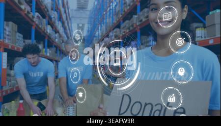 Smiling woman wearing blue Volunteer tee holding Donate sign in depot with HUD overlays, copy space Stock Photo