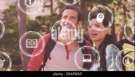 Couple in gray henley red-sleeved and green plaid gazing upward in forest, with backpacks, AR icons Stock Photo
