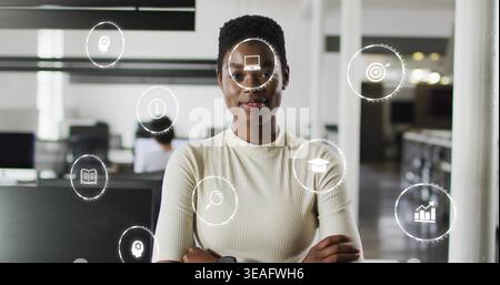 Posing woman wearing top, watch, crossing arms in office showing hologram icons, monitors Stock Photo