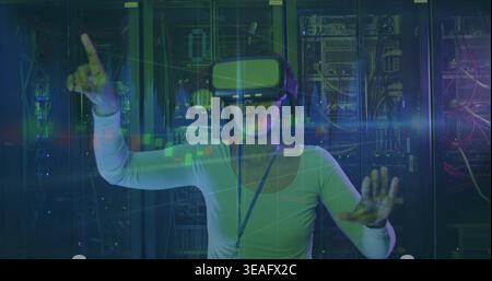 Standing IT woman wearing long-sleeve top and lanyard, using VR headset in server room Stock Photo