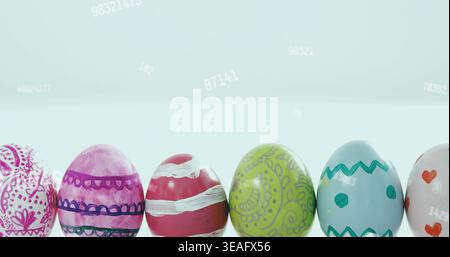 Displaying row of painted glossy eggs on white table with pale blue gradient and faint numbers Stock Photo
