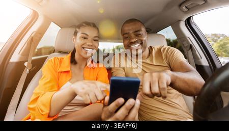 Young African American couple using smartphone together inside car Stock Photo